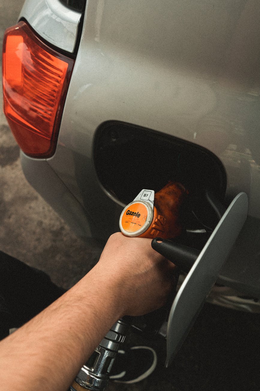 person refilling gasoline on gas tank
